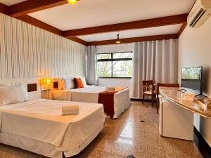 a hotel room with two beds and a television at Villa Nautilus Be Happy in Fortaleza