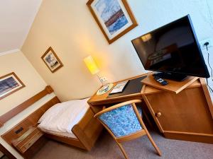 a bedroom with a desk with a television and a bed at Gasthaus Beinker in Ostercappeln