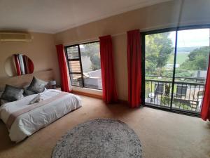a bedroom with a bed and a large window at The Mansion Lodge in Hartbeespoort