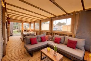 a screened in porch with a couch and a table at Mobilhome La Pause Océane - La Plage in Mimizan-Plage