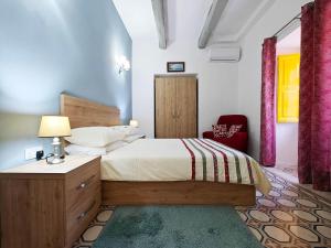 a bedroom with a bed and a red chair at Dar Marija in Valletta