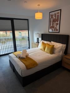a bedroom with a large bed with yellow pillows at Berkeley Square Apartments by StaySavvy Accommodation in Manchester