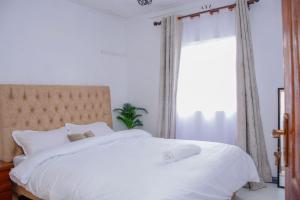 a bedroom with a white bed with a large window at Meg Cozy Homes Executive 1Bedroom and 2Bedroom Apartments Near Rupa Mall The Noble Hotel & Poa Place Resort in Eldoret