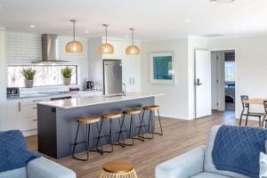 a kitchen and living room with a counter and stools at Arthurs Vineyard - Sleeps 10 in Martinborough