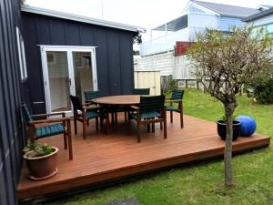 a wooden deck with a table and chairs at Claras Togs and Towels in Waihi Beach