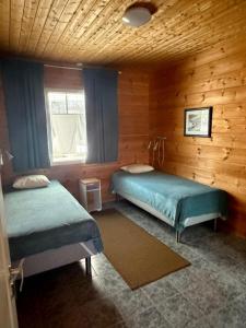a bedroom with two beds in a log cabin at Taljatie Apartments in Rovaniemi
