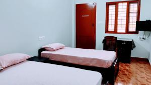 a bedroom with two beds and a red door at Thomson Kylas Rooms in Ettumānūr