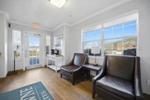 a living room with two chairs and a desk and windows at HomeTowne Studios by Red Roof Atlanta - Peachtree Corners in Norcross