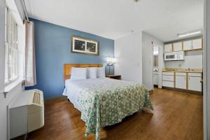 a bedroom with a bed and a blue wall at HomeTowne Studios by Red Roof Atlanta - Peachtree Corners in Norcross