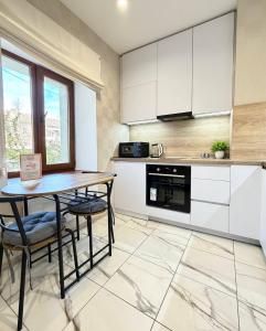 a kitchen with white cabinets and a table and chairs at Троїцька площа 3 Квартира Самий Центр Окремий Вхід in Dnipro