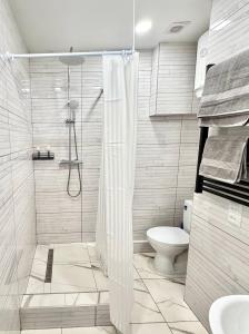 a white bathroom with a shower and a toilet at Троїцька площа 3 Квартира Самий Центр Окремий Вхід in Dnipro