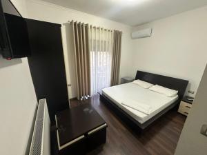 a small bedroom with a bed and a table at Hotel Yjet in Pogradec