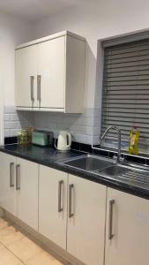a kitchen with white cabinets and a sink at PLUS Properties Oxford 3 in Stoke on Trent +10 photos