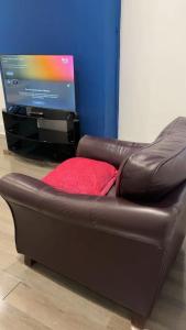 a brown leather couch in front of a television at PLUS Properties Oxford 3 in Stoke on Trent