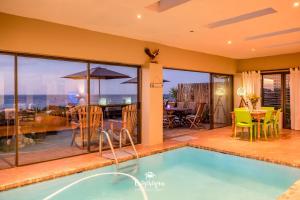 a house with a swimming pool and a patio with a table at Boardwalk in Britannia Bay