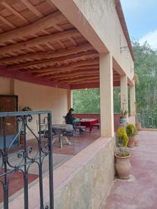 a porch with awning and a person sitting at a table at Auberge Kasbah Ait Marghad in Tamellalt