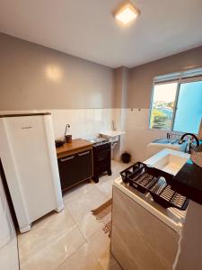 a kitchen with a white refrigerator and a sink at Apt 404 BL 6 entrada de londrina in Cambé +4 photos