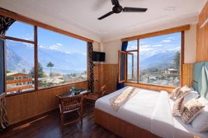 a bedroom with a bed and large windows at New Suraj Inn - Nestled near Hadimba Temple ! Rooftop Cafe ! Private Parking in Manāli