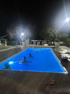 two people in a blue swimming pool at night at Espaço Vip in Brasília