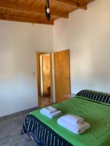 a bedroom with a green bed with towels on it at Apart Cerezos in Los Antiguos