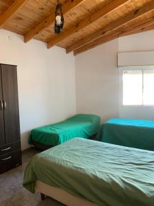 two beds in a room with wooden ceilings at Apart Cerezos in Los Antiguos