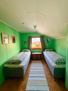 two beds in a room with green walls and a window at Cozy House by the Lake in Vestvågøya