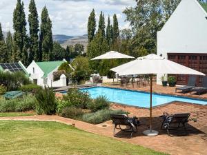 a swimming pool with two chairs and an umbrella at The Gables-Clarens in Clarens