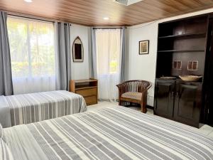 a bedroom with two beds and a chair and a window at Tropical Bliss Pool Wi-Fi BBQ Near Quepos Manuel Antonio in Quepos +26 photos