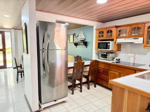 a large kitchen with a stainless steel refrigerator at Tropical Bliss Pool Wi-Fi BBQ Near Quepos Manuel Antonio in Quepos