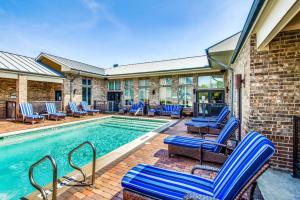 a swimming pool with blue chairs next to a building at King Aqua Suite Walkable Legacy West King Bed, Pool & Gym in Plano