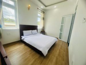 a bedroom with a white bed and two windows at villa danisa hoa in Khu Chi Lăng