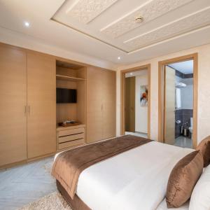 a bedroom with a large bed and a tv at Résidence La Place in Laayoune