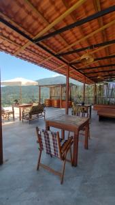 a patio with wooden tables and benches and a roof at Segunda Casa-CASA DE TEMPORADA in Paraty