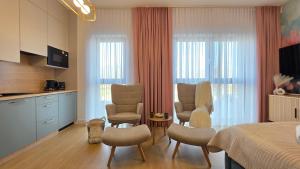 a bedroom with a bed and chairs and a kitchen at Boszkowo Horizon Park Apartament 14 "Laguna" in Boszkowo