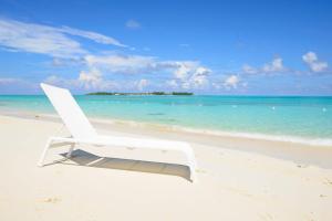 a white chair sitting on a beach near the ocean at Cable Beach condo with ocean views in Nassau
