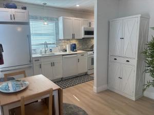 a kitchen with white cabinets and a table in it at Seaside Retreat Cottages #4 in Clearwater Beach