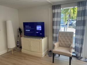 a living room with a tv on a cabinet and a chair at Seaside Retreat Cottages #4 in Clearwater Beach