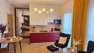 a kitchen with red cabinets and a table and chairs at Boszkowo Horizon Park Apartament 15 "Bordowy" in Boszkowo