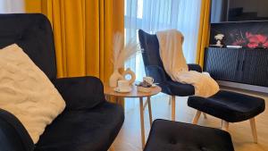 a living room with two chairs and a table at Boszkowo Horizon Park Apartament 15 "Bordowy" in Boszkowo +6 photos