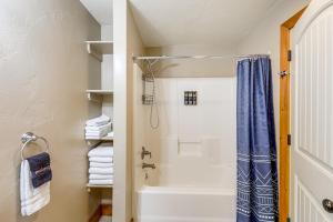 a bathroom with a tub and a shower with a blue shower curtain at Columbia Falls Private Retreat: Pool Table & Deck! in Columbia Falls +36 photos