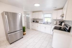 a kitchen with white cabinets and a stainless steel refrigerator at Spacious Home with Fire Pit & Game Room Near Yale in Hamden