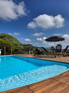 a pool with chairs and umbrellas on a deck at Pousada Capão Fôrro in São Roque de Minas