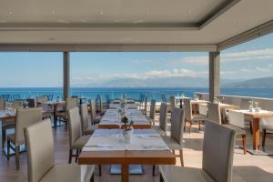 restauracja ze stołami i krzesłami oraz widokiem na ocean w obiekcie Miramare Resort & Spa w mieście Ajos Nikolaos