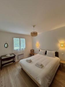 a bedroom with a large white bed and a table at La Maison du Square in La Teste-de-Buch