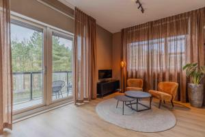 ein Wohnzimmer mit Tisch, Stühlen und Fenstern in der Unterkunft Hotel Ameland in Nes