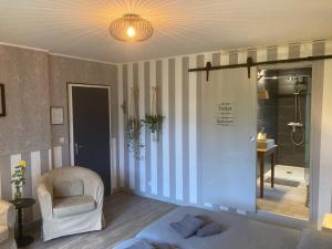 a room with a bed and a chair and a shower at La Chêneraie Chambres d'hôtes-B&B in Payrac