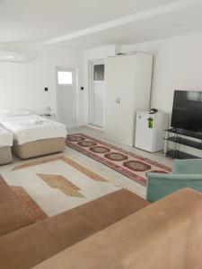 a white bedroom with a bed and a tv at Jasmin Apart Otel in Göcek