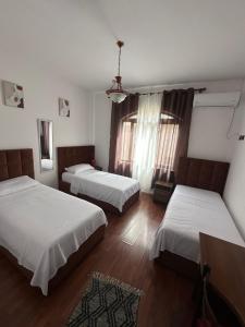 a room with two beds and a table and two windows at Kruja Grande Hotel in Krujë
