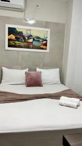 a bed with white pillows and a painting on the wall at Pousada Refúgio Do Cangaço in Piranhas +6 photos