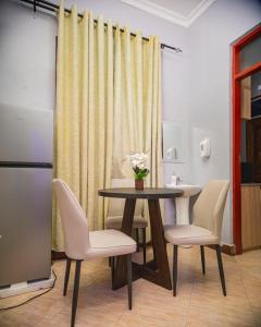 a dining room table with chairs and a table with flowers on it at JIV Luxury Homes in Mwanza